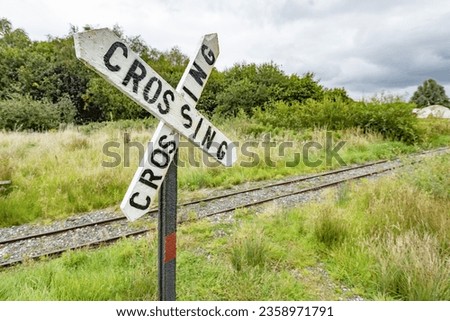 "cross road" portion of sign with railroad tracks in background crossroads concept