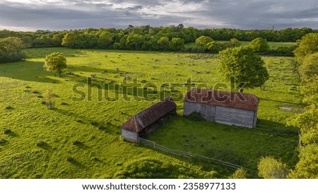 Old lonely barn in a green field in sunset light on a spring evening, west sussex, uk