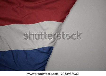 big waving national colorful flag of netherlands on the gray background. macro