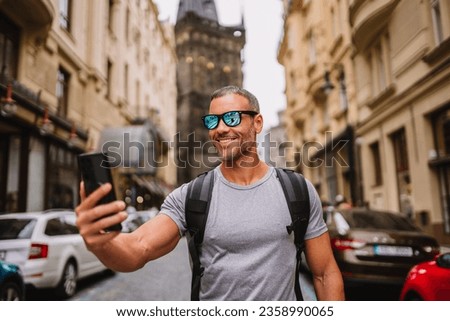 Tourist smiling, taking a selfie on the street on smartphone . Royalty-Free Stock Photo #2358990065