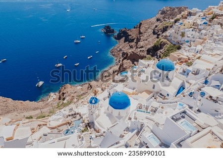 Panorama of Greek Orthodox Churc with blue dome and blue vibrant sea. Aerial view Santorini, Greece. Royalty-Free Stock Photo #2358990101