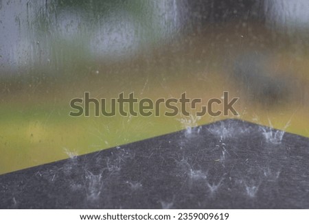 raindrops hitting black patio table green grass in background rainy day at the cottage outside in the rain droplets splashing on black table stormy day horizontal environmental backdrop or background