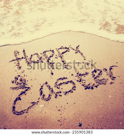Sign "Happy Easter" on the sandy beach by the ocean