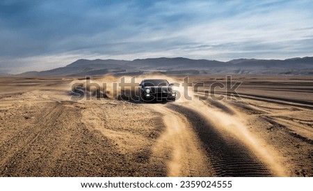 A car drives through a dusty desert, kicking up dust. An off road car driving on the desert  Royalty-Free Stock Photo #2359024555
