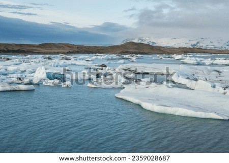 frozen lake in winter backed by mountains Royalty-Free Stock Photo #2359028687