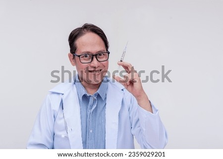 A crazed, scary and maniacal doctor tells someone to come closer while eagerly holding a syringe and with an evil grin. Isolated on a white background. Royalty-Free Stock Photo #2359029201