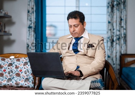 Cheerful young businessman in formal dress working online using laptop at home, freelance business from home