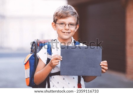 Happy little kid boy with glasses and backpack or satchel. Schoolkid on the way to school. Healthy adorable child outdoors On desk First day second grade in German. Back to school. Royalty-Free Stock Photo #2359116733