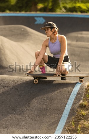 woman skating in skatepark at sunrise with longboard cap and short hair
