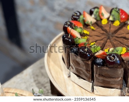 Dark chocolate tart made with 100% cocoa and various nuts and seeds. Toping mixed fruits kiwi strawberry blueberry cherry.
Chocolate Cake homemade on wooden plate. Bakery picture free space for text. 