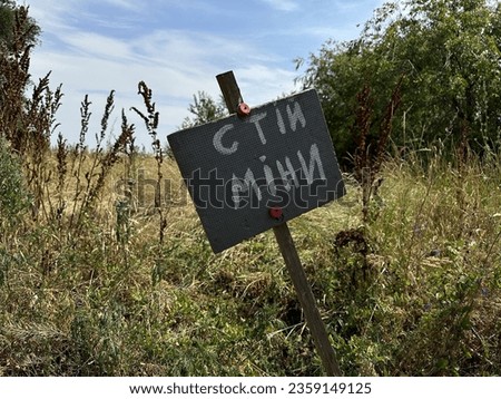Danger sign mine in Ukrainian near an agricultural field during war in Ukraine, translation: "Stop Mine"