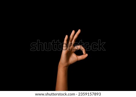 Hand making okay sign on black background, sign of approval and good mood