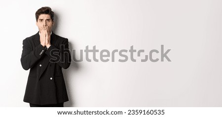 Portrait of shocked handsome businessman in suit, reacting to terrible situation, gasping and covering mouth with hands, standing startled against white background. Royalty-Free Stock Photo #2359160535