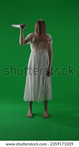 Full-size vertical green screen, chroma key shot of a posessed female, woman figure, ghost, poltergeist, zombie raising, pulling out a knife, stabbing the air. Hair is covering her face.
