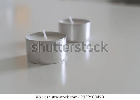 Tealight on a white table, neutral tones, white home, minimalistic studio apartment, no people, candlelight fire, calm atmosphere, flicker light of a small candle, winter aesthetics, neutral tones