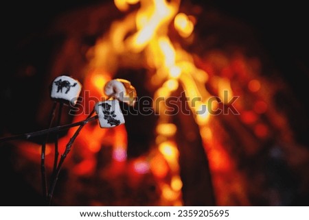 Marshmallows with Halloween pictures over fire. Funny leisure on traditional spooky holiday for children and families.