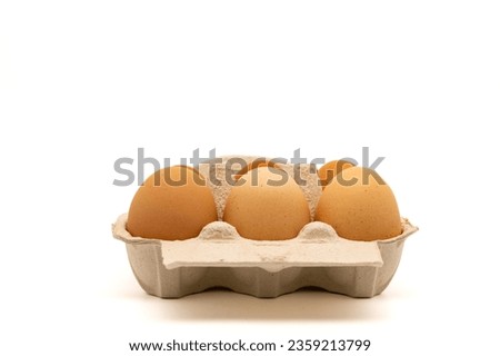 Cardboard egg box with six organic chicken eggs isolated on white background with copy space. Side view.