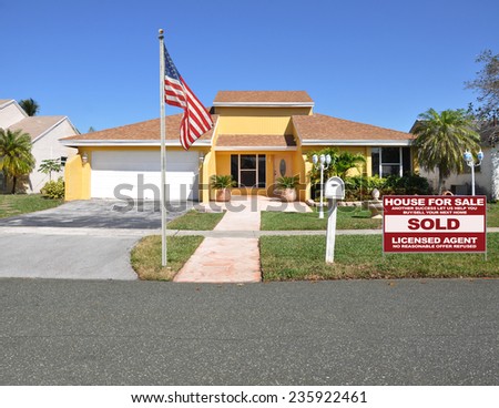 American flag pole Real Estate sold (another success let us help you buy sell your next home) sign suburban ranch home residential neighborhood sunny blue sky USA