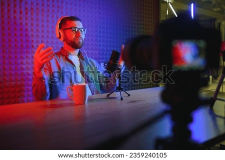 Young man recording or streaming podcast using microphone at his small broadcast studio. Content creator