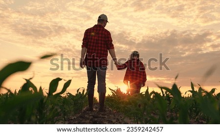 Dad daughter hold hands in field. Father, child walk on field, sunset. Kid girl, dad go hand in hand, field corn sprouts. Family farming business. Agricultural industry. Growing corn, organic food Royalty-Free Stock Photo #2359242457
