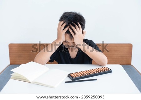 Asian child is worried. There is an intention to use the abacus in studying mathematics. Educational concept Social distancing, staying at home, presenting a modern educational way of life.