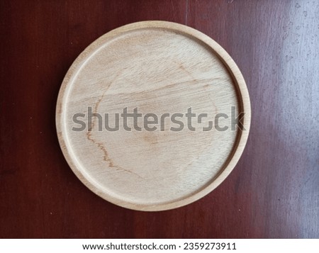 Round coasters made of wood on a dark brown table with light directed from the right.