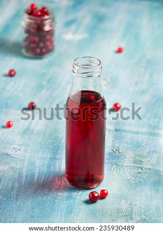 Cranberry fruit drink in bottle on a blue background. Selective focus