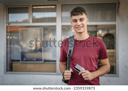 portrait of teenager man stand in front of bank ATM hold credit card