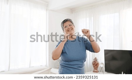 Cheerful asian elderly woman enjoy dancing in living room at home. Happy senior woman dancing and having fun. Elderly woman leisure weekend at home. Asian senior lifestyle