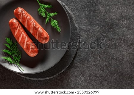 Grilled sausages with herbs, on slate stone plate round, dark background, top view
