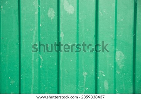 Photo of an old green corrugated iron fence with dirt stains.