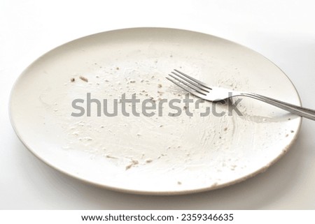 Dirty plate with a fork on the table. Photo can be used for the concept of how to clean the plate after food.