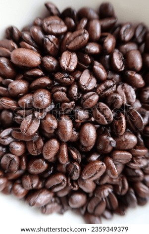 Close-up image of dark roasted coffee beans. Dark brown greasy coffee beans, white background, natural light, detail of coffee beans, coffee barista atmosphere, no people