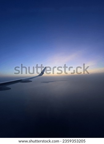 Picture of an airplane wing and an island in the air