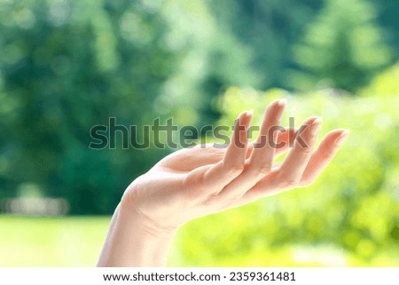 Waving hand against the background of the garden. Hope symbol.