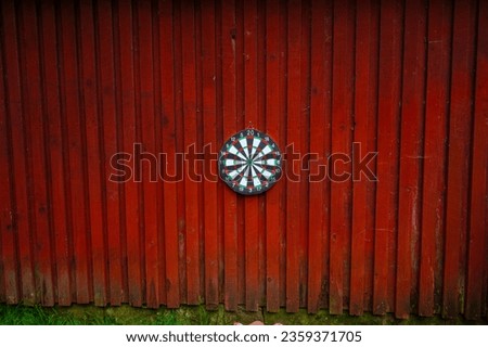 Dart board hanging on a red wooden wall.