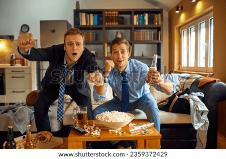 Two young friends cheering for their team during an basketball match on the tv in the living room