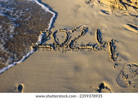 The number 2024 written in the sand on the beach. new year 2024 concept with text on sun rising sky. Creative Concept. 
