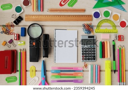 Colorful school supplies designed on wooden table, with blank checkered notebook,top view