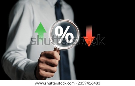 Businessman holding magnifying glass with percentage icon and up and down arrow icon with graph indicator, financial interest rates and mortgage rates. Interest Rates Stocks Finance.