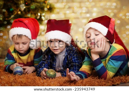 Little boys near a Christmas tree. Children in cap of Santa