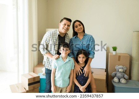 Happy hispanic family of four with two kids smiling feeling cheerful while moving into a new house together Royalty-Free Stock Photo #2359437857