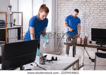 Group Of Janitors Cleaning The Modern Office With Caution Wet Floor Sign