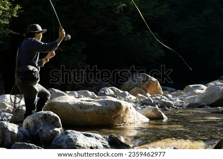 Japanese man fly fishing in a mountain stream in Japan
