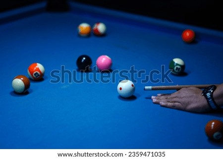 The hand holding the billiard cue, ready to make a precise strike on the billiard ball on the billiard table in a game of billiards. Sport and game photography.