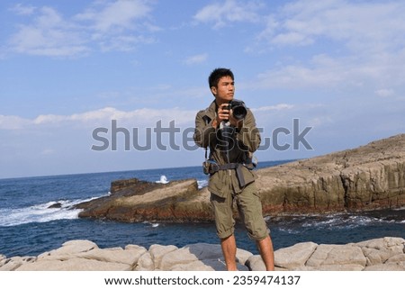 A young man travelling on stony area. Landscape  photographer  with the camera in his hands walking on rocky terrain and wearing backpack