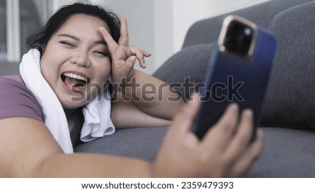 Fat Asian woman taking selfie with smartphone on sofa after exercising