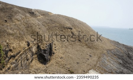Summer view of a hill with dry long grass and sea around