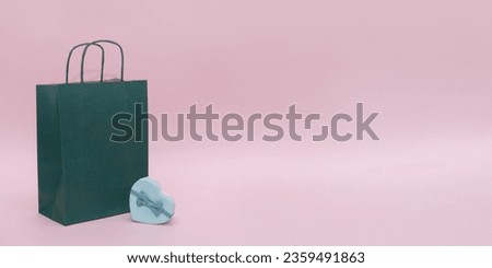 Shopping bag with heart shaped gift box on pink background. Copy space, holiday concept. High quality photo