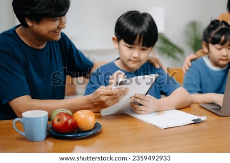 Asian Overjoyed kids sitting on sofa with cheerful parents, watching funny video on computer. Happy married couple enjoying spending weekend time with children, looking at laptop and tablet at house

 Royalty-Free Stock Photo #2359492933